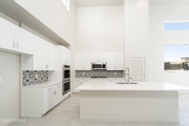 kitchen with sink, white cabinetry, stainless steel appliances, and a high ceiling