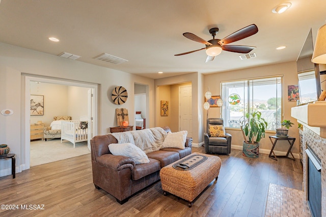 living room featuring a fireplace, hardwood / wood-style floors, and ceiling fan