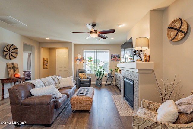 living room with ceiling fan, dark wood-type flooring, and a tile fireplace