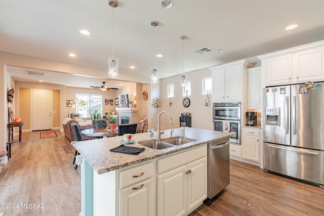 kitchen featuring a kitchen island with sink, white cabinets, sink, ceiling fan, and stainless steel appliances