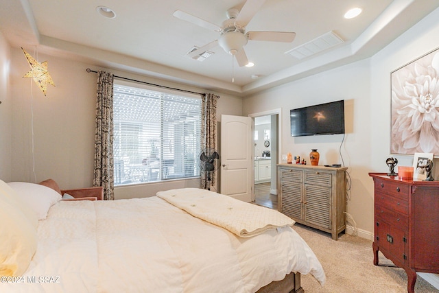 carpeted bedroom with ceiling fan, a raised ceiling, and ensuite bathroom