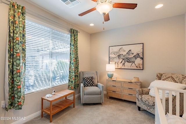 carpeted bedroom with a crib, multiple windows, and ceiling fan