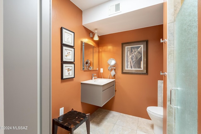 bathroom with tile patterned floors, a shower with door, vanity, and toilet