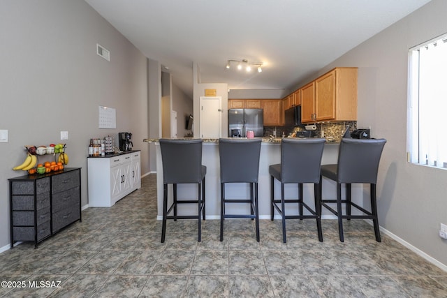 kitchen featuring backsplash, a kitchen breakfast bar, kitchen peninsula, and stainless steel refrigerator with ice dispenser