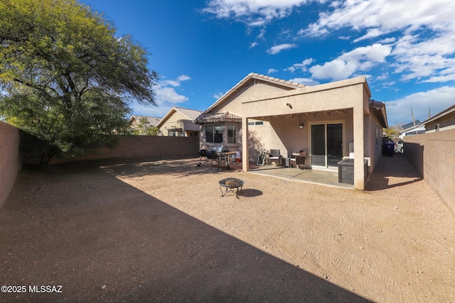 rear view of property with a patio and an outdoor fire pit