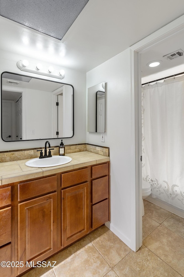 bathroom featuring tile patterned floors, walk in shower, vanity, and toilet