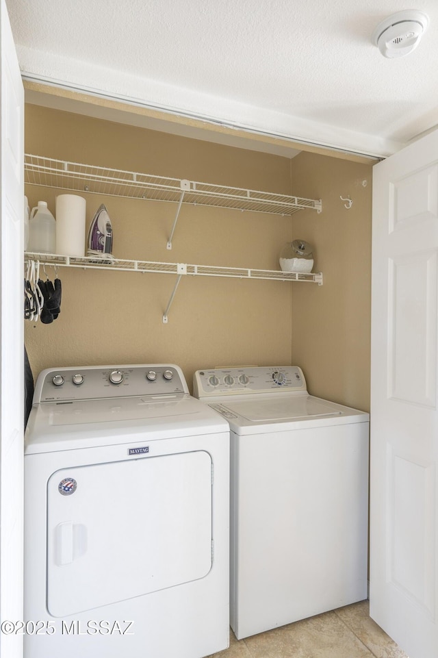 laundry room featuring washer and dryer, light tile patterned flooring, and a textured ceiling