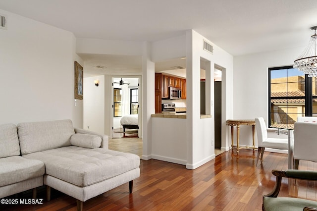 living room featuring hardwood / wood-style floors, plenty of natural light, and ceiling fan with notable chandelier