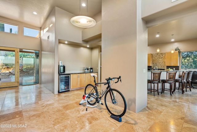 kitchen featuring a high ceiling, light brown cabinets, and beverage cooler