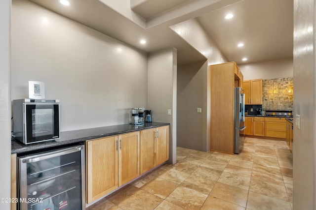 kitchen featuring decorative backsplash, stainless steel refrigerator, dark stone countertops, and wine cooler