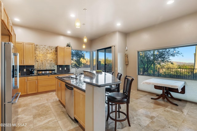 kitchen with appliances with stainless steel finishes, sink, a center island with sink, decorative light fixtures, and dark stone countertops