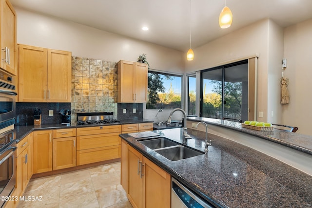 kitchen featuring decorative backsplash, dark stone counters, stainless steel appliances, sink, and hanging light fixtures