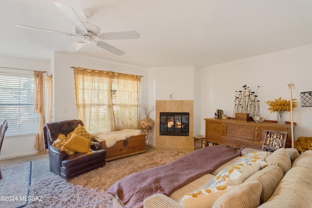 carpeted bedroom featuring a tile fireplace and ceiling fan