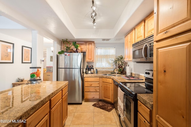 kitchen featuring sink, rail lighting, stainless steel appliances, a tray ceiling, and light tile patterned floors