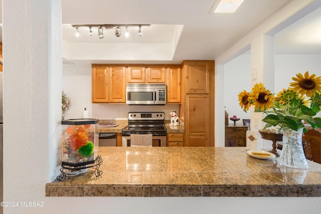 kitchen featuring kitchen peninsula, stainless steel appliances, and track lighting