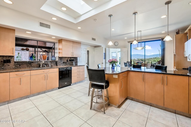 kitchen featuring kitchen peninsula, decorative light fixtures, sink, black dishwasher, and dark stone countertops