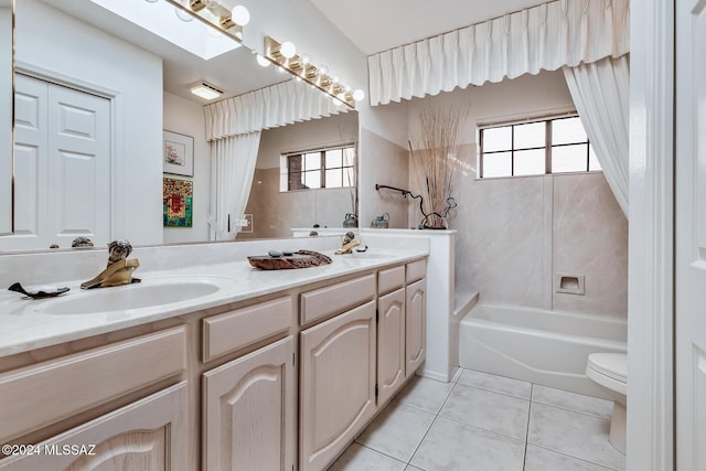 full bathroom featuring tile patterned flooring, tiled shower / bath, toilet, a skylight, and vanity