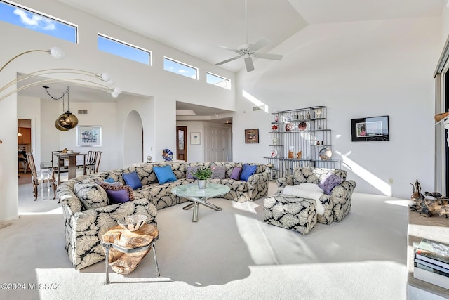 carpeted living room featuring ceiling fan and a towering ceiling