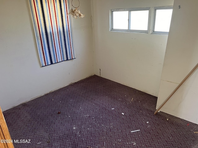 unfurnished room featuring dark colored carpet