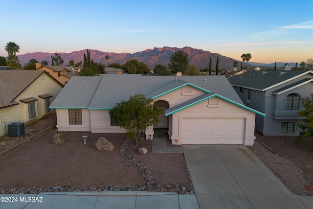 ranch-style home with central air condition unit, a mountain view, and a garage