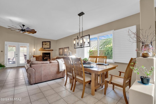 dining area with light tile patterned floors, ceiling fan with notable chandelier, and vaulted ceiling