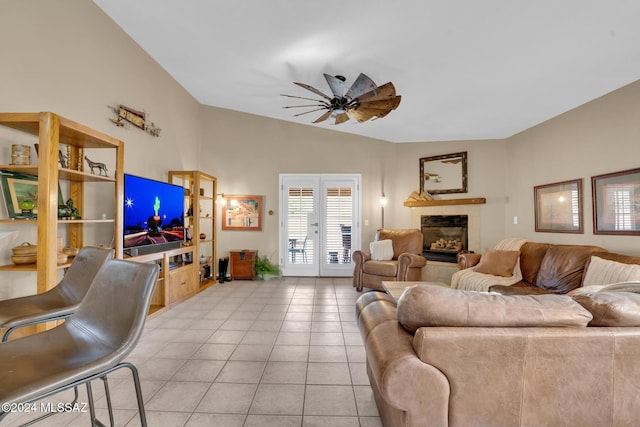 living room featuring lofted ceiling, french doors, ceiling fan, light tile patterned flooring, and a tiled fireplace