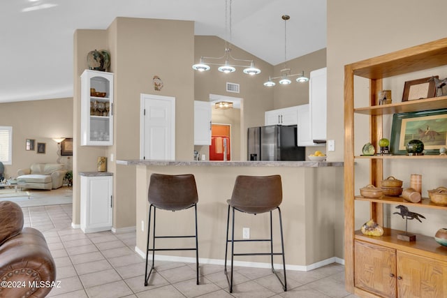 kitchen with a breakfast bar, high vaulted ceiling, white cabinets, kitchen peninsula, and stainless steel fridge with ice dispenser