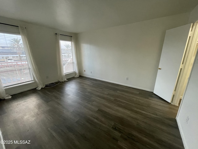 empty room featuring dark wood finished floors and baseboards