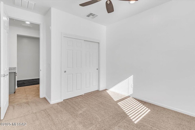 unfurnished bedroom with light colored carpet, a closet, and ceiling fan