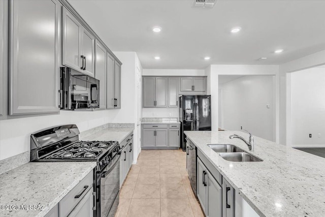 kitchen featuring gray cabinetry, sink, light stone counters, light tile patterned floors, and black appliances