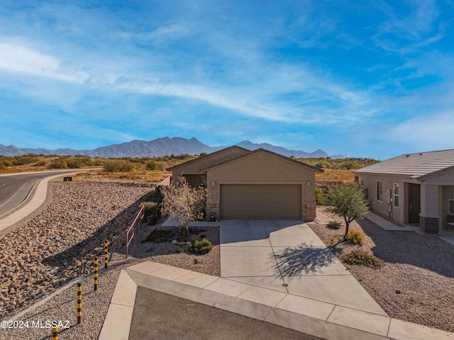 view of front of home featuring an attached garage, driveway, a mountain view, and stucco siding