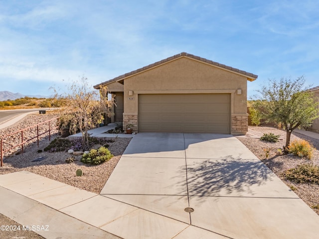 ranch-style home featuring concrete driveway, stone siding, and stucco siding