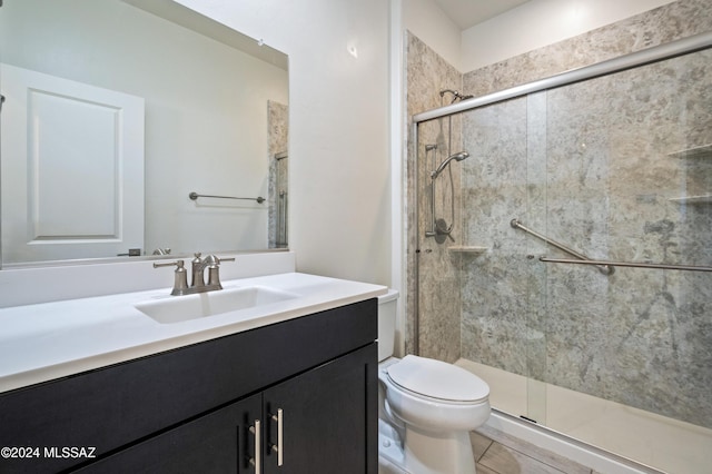 bathroom featuring tile patterned floors, vanity, toilet, and a shower with door