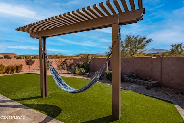 view of yard featuring a pergola, a fenced backyard, and a mountain view