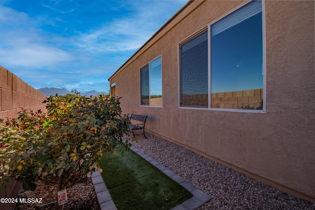 view of side of property with stucco siding, fence, and a mountain view