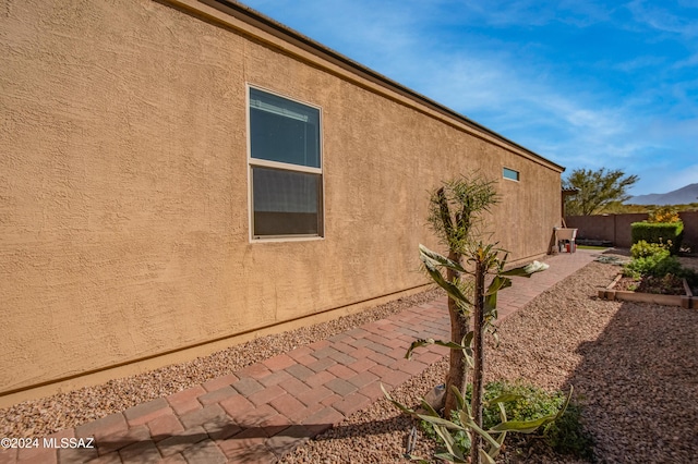 view of side of home featuring stucco siding and fence