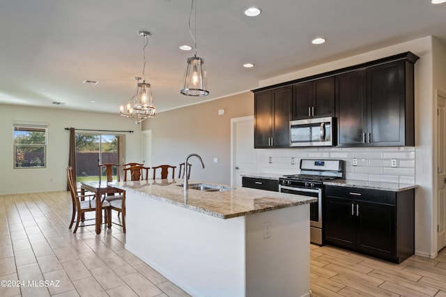 kitchen featuring a center island with sink, backsplash, sink, and stainless steel appliances