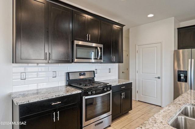 kitchen with sink, light stone countertops, stainless steel appliances, and tasteful backsplash