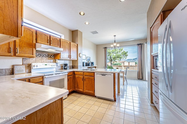 kitchen featuring sink, hanging light fixtures, kitchen peninsula, a chandelier, and white appliances