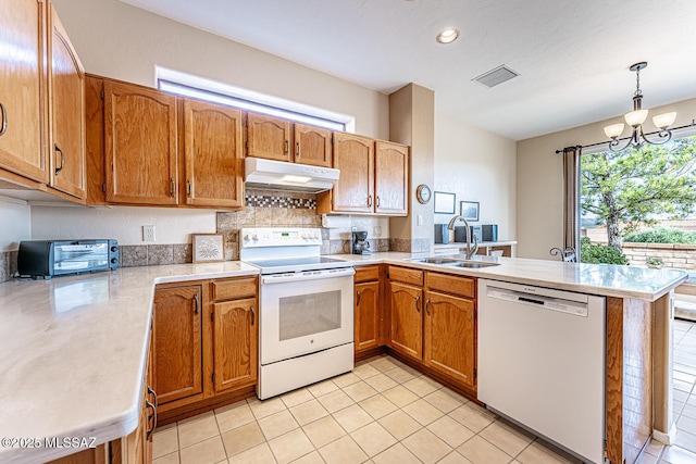 kitchen with pendant lighting, white appliances, sink, kitchen peninsula, and a chandelier