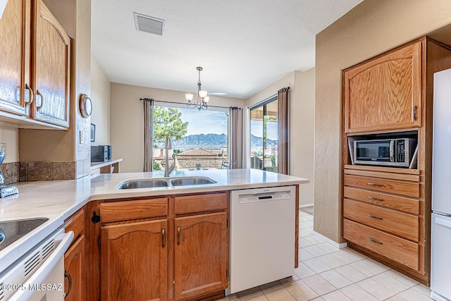 kitchen featuring an inviting chandelier, white dishwasher, sink, light tile patterned floors, and decorative light fixtures