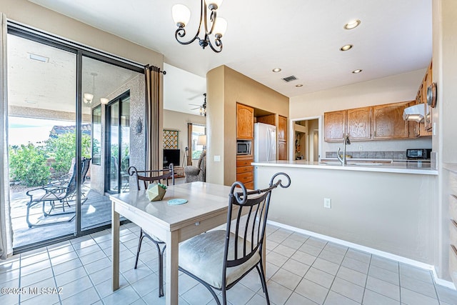 tiled dining room with sink and ceiling fan with notable chandelier