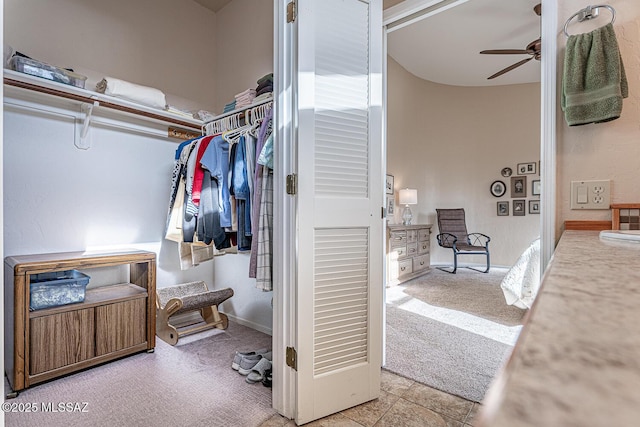 walk in closet with ceiling fan and light colored carpet