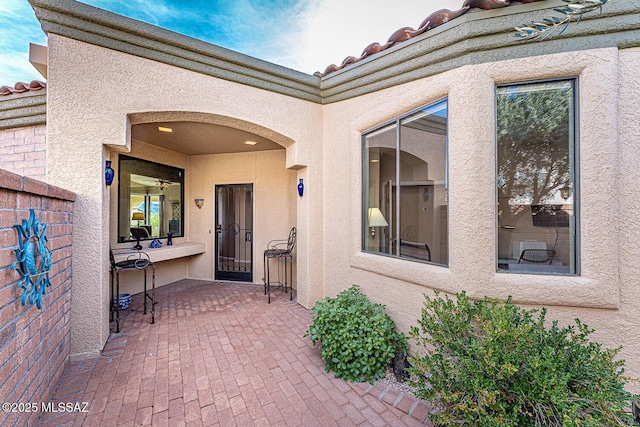 view of exterior entry with a patio area