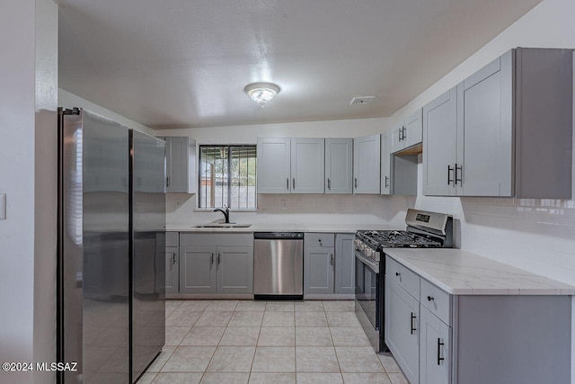 kitchen featuring gray cabinetry, decorative backsplash, sink, and appliances with stainless steel finishes