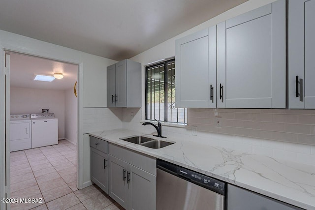 kitchen featuring stainless steel dishwasher, light stone countertops, independent washer and dryer, and sink