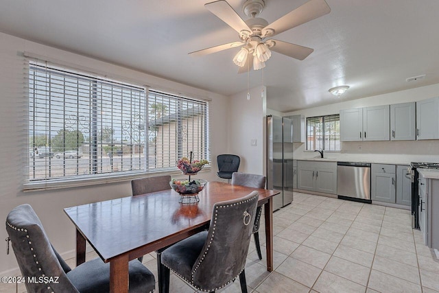 tiled dining room featuring plenty of natural light, ceiling fan, and sink