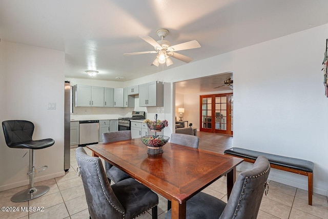 tiled dining room featuring ceiling fan and french doors