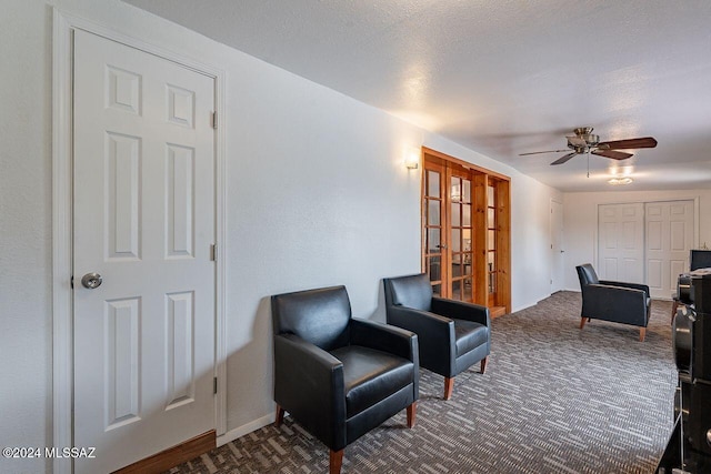 living area with carpet flooring, ceiling fan, and a textured ceiling