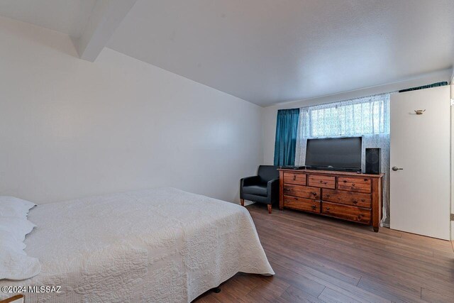 bedroom featuring beamed ceiling and dark hardwood / wood-style floors